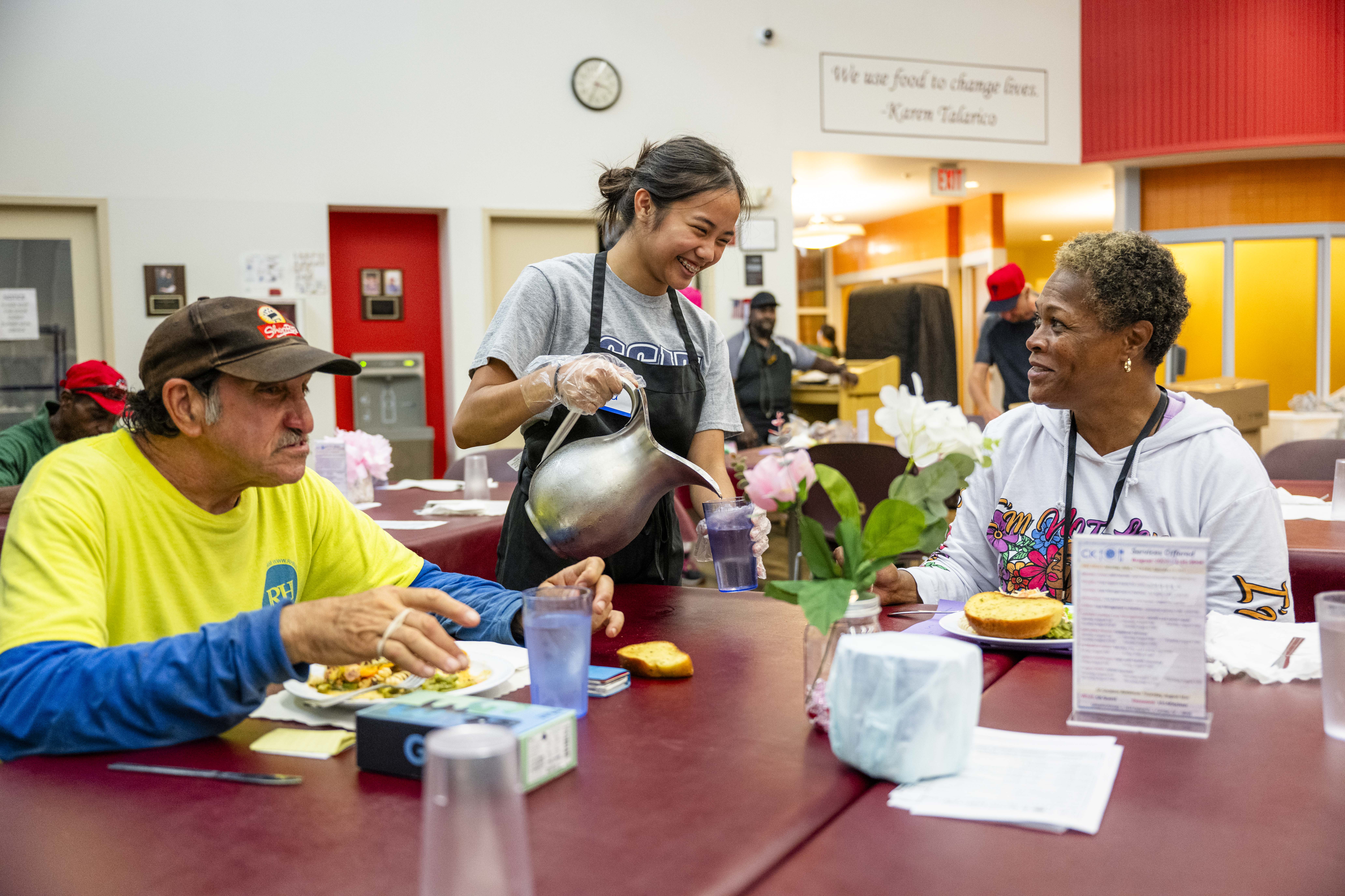 Volunteer serving free meals to food insecure guests at Cathedral Kitchen